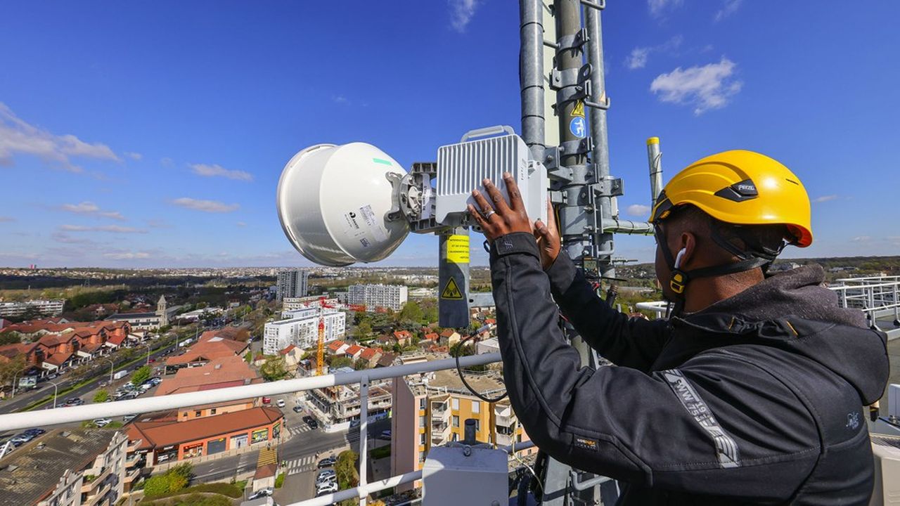 Installation par O+M, societe "operation et Maintenance" d'une antenne FH, faisceau hertzien, de telephonie mobile de l'operateur Bouygues Telecom equipee pour la 5G (cinquieme generation) sur la toiture d'un immeuble d'habitation situee dans une zone residentielle.  

 Technicien Telco procedant a l'alignement du signal hertzien avec une autre antenne situee a 4 kilometres, connexion du signal,